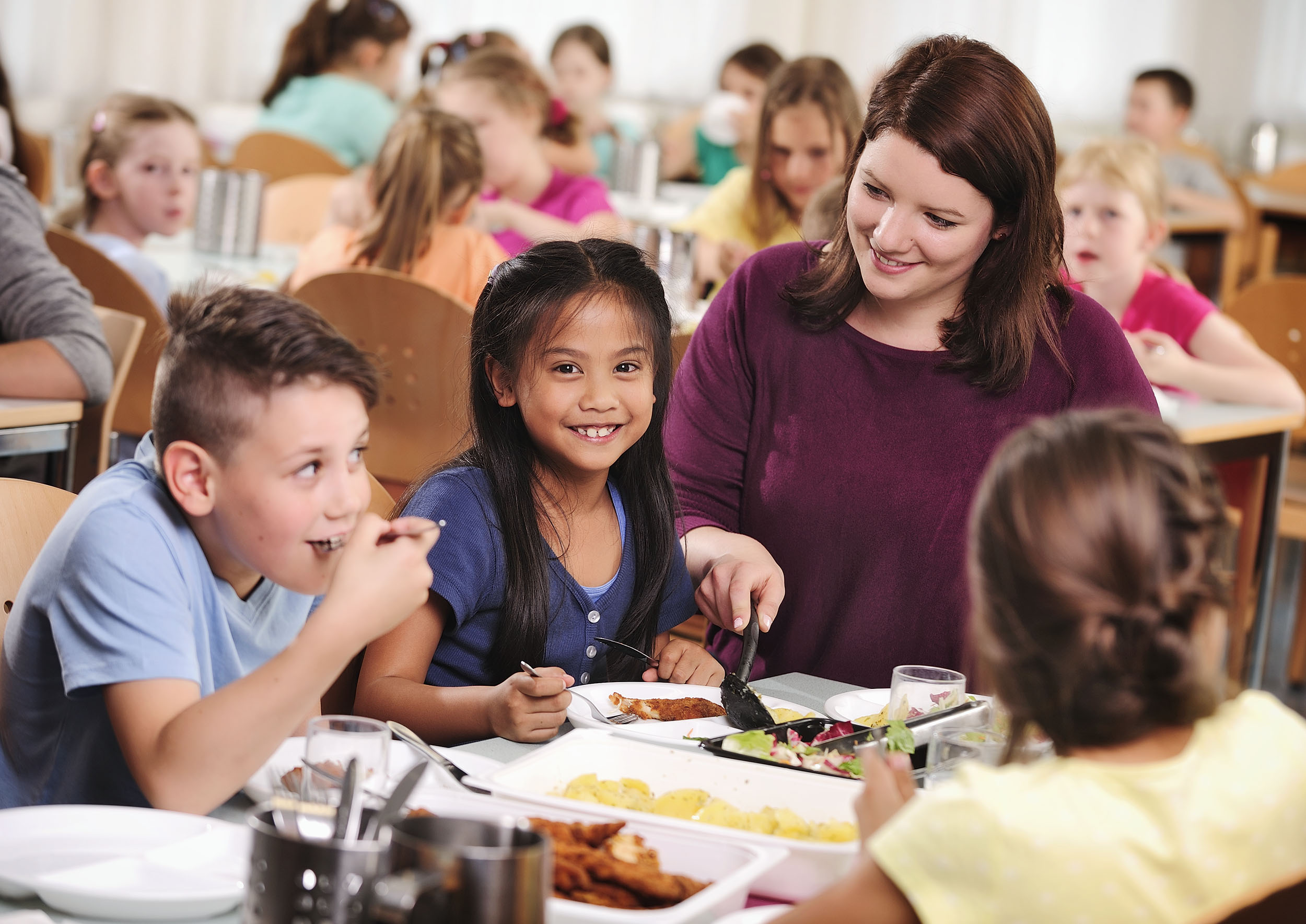 Kinder mit Hortbetreuerin beim Mittagessen