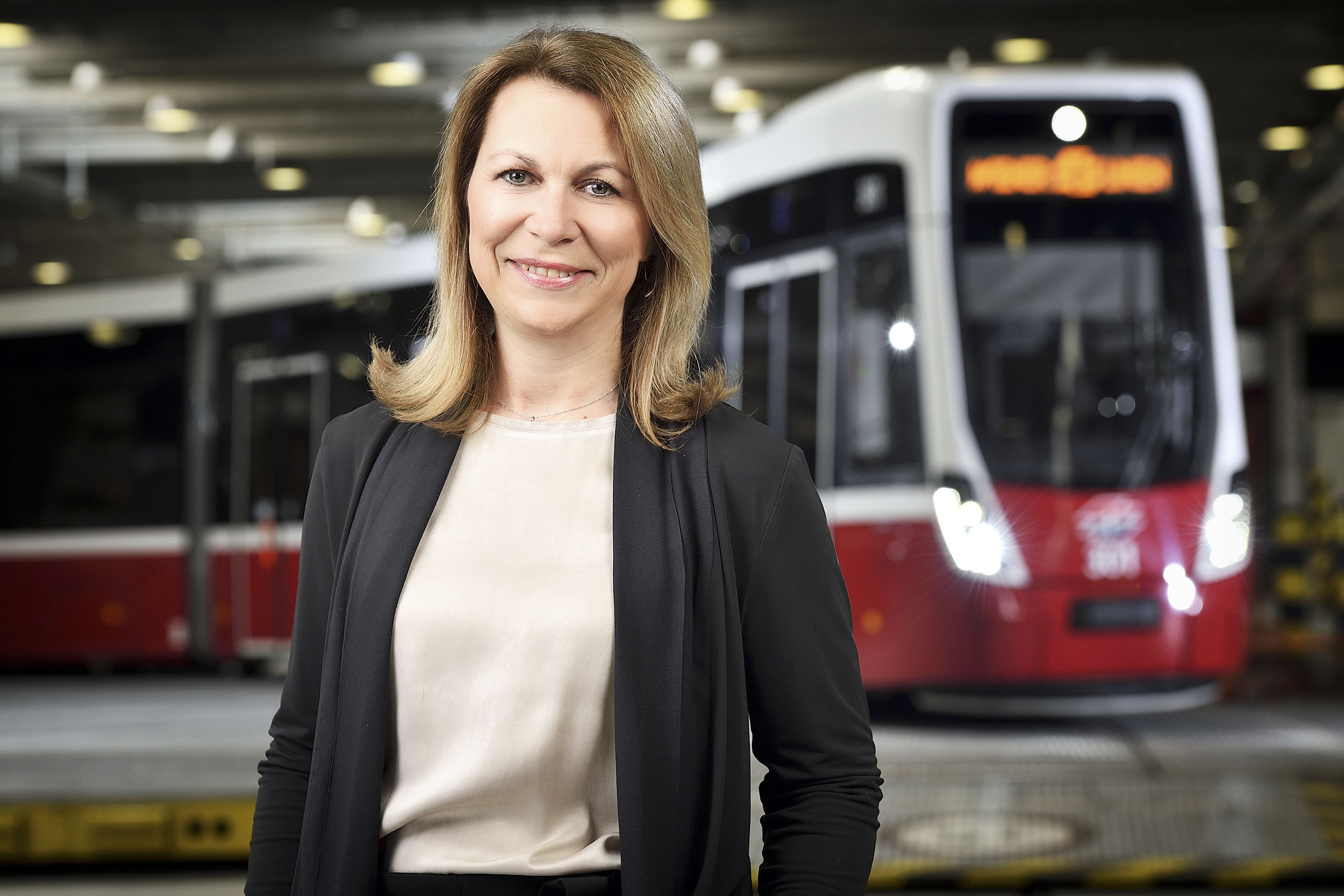 Portrait der Wiener Linien-Geschäftsführerin Alexandra Reinagl, im Hintergrund eine Flexity-Straßenbahn